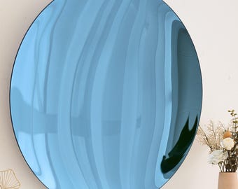 May include: A round, blue, wavy mirror with a reflective surface. The mirror is hanging on a white wall.