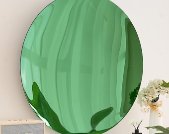 May include: A round, green mirror with a reflective surface. The mirror is hanging on a white wall.