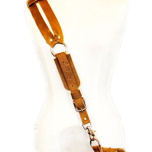 May include: A brown leather shoulder strap with a silver buckle and ring. The strap is adjustable and has a hook at the end.