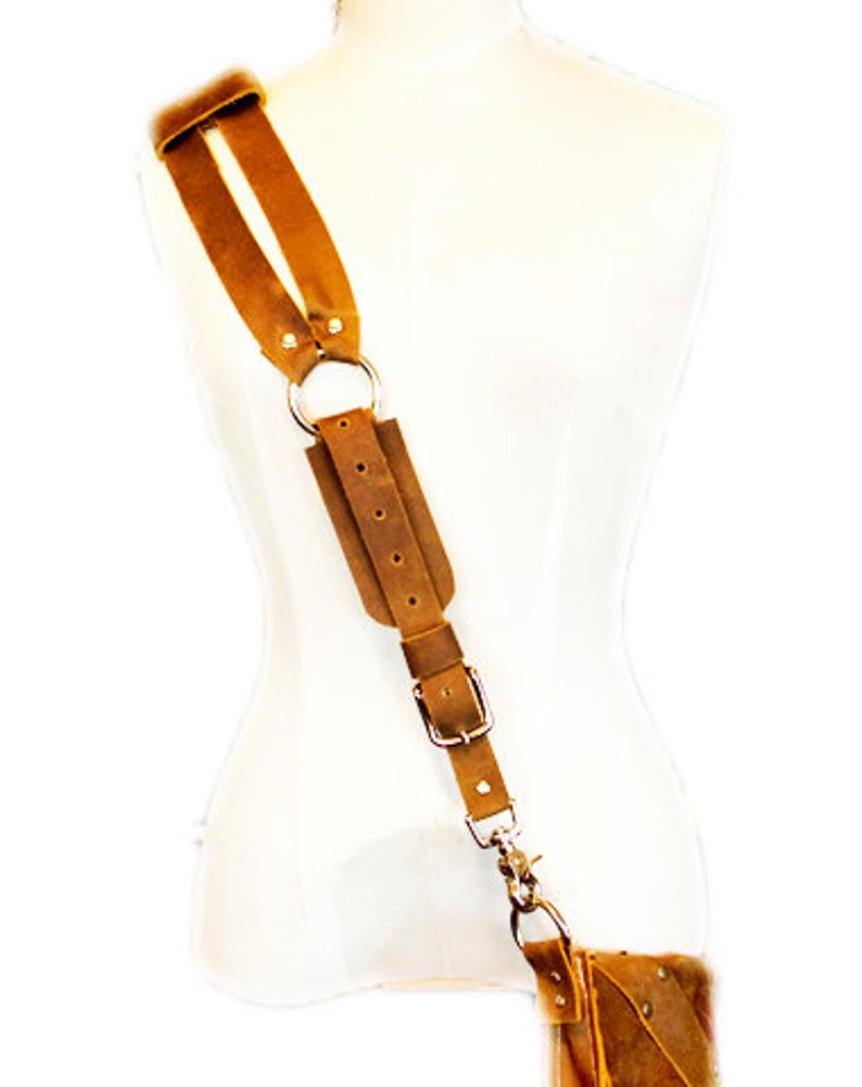 May include: A brown leather shoulder strap with a silver buckle and ring. The strap is adjustable and has a hook at the end.