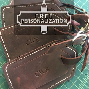 May include: Four brown leather luggage tags with white stitching. The tags are personalized with the initials "CWR". The tags have a metal loop and a leather strap. The image includes the text "FREE PERSONALIZATION".