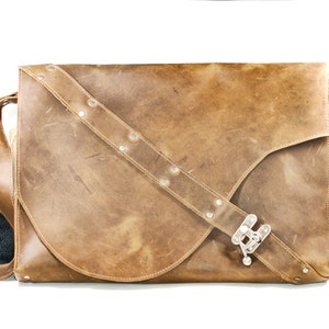 May include: A brown leather messenger bag with a silver buckle and a strap with silver studs.