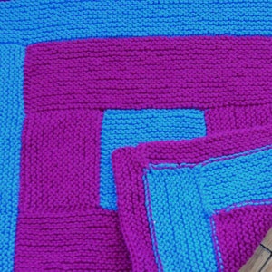 May include: A knitted blanket with a geometric pattern in shades of pink and blue.