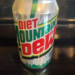 May include: A silver Diet Mountain Dew soda can with green and white stripes. The can features the words "Diet Mountain Dew" in red, green, and white, with "Est. 1948" below. A green forest graphic is at the bottom.