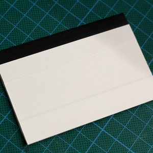 May include: A white label with a black border. The label is blank and ready to be written on.