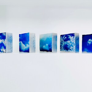 Row of small, bright blue and white cloud art; clouds artworks with silver foil edges; clouds with silver linings