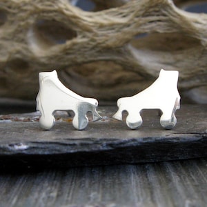 May include: A pair of silver roller skate earrings. The earrings are in the shape of a roller skate with four wheels. The earrings are small and delicate.