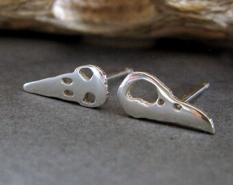 May include: A pair of silver earrings shaped like bird skulls. The earrings are small and delicate, with a simple design.
