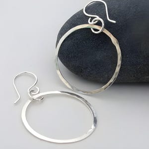 May include: A pair of silver hoop earrings with a hammered finish. The earrings are simple and elegant, and they would make a great gift for any occasion.