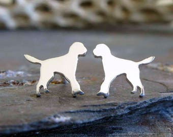 Può includere: Un paio di orecchini d'argento a forma di silhouette di cane. Gli orecchini sono piccoli e delicati, e sono perfetti per chiunque ami i cani.
