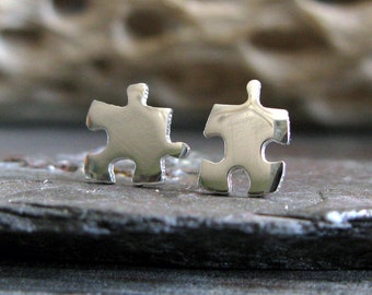 May include: A pair of silver puzzle piece earrings. The earrings are small and delicate, and they are perfect for anyone who loves puzzles.