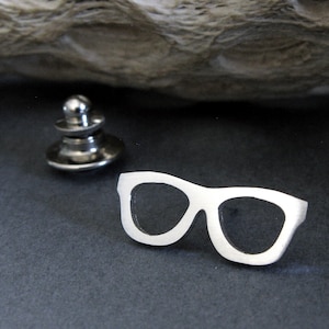 May include: Silver-toned metal lapel pin shaped like a pair of sunglasses.