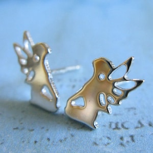 May include: A pair of silver stud earrings with a unique abstract design. The earrings are made of metal and have a shiny finish.