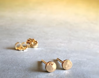 Op de afbeelding: Een paar gouden gehamerde schijf oorbelletjes. De oorbelletjes zijn klein en hebben een eenvoudig ontwerp.