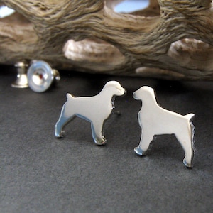 May include: A pair of silver earrings shaped like a dog silhouette. The earrings are small and delicate, and they would make a great gift for any dog lover.