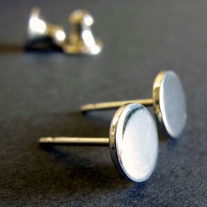 May include: A pair of silver stud earrings with round, smooth, flat tops.