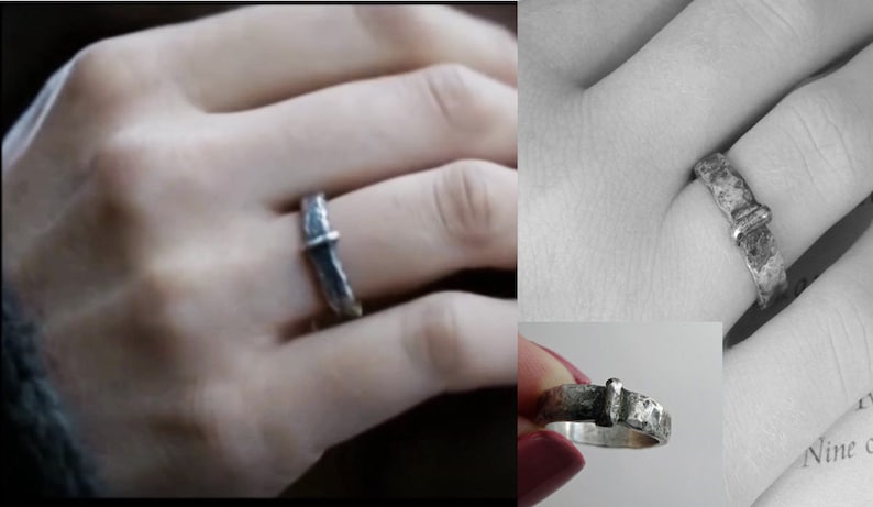 May include: A silver ring with a textured band and a rectangular accent. The ring is shown on a hand, highlighting its design and craftsmanship. The ring's style is rustic and unique.