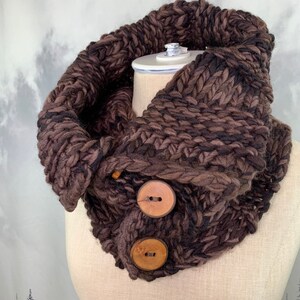 May include: A brown and black knitted infinity scarf with two large wooden buttons.