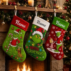 Könnte beinhalten: Drei Weihnachtsstrümpfe hängen an einem Kaminsims. Der erste ist grün mit rotem Umschlag und Grinch-Motiv. Der zweite ist grün mit weißem Umschlag und Grinch-Grafik. Der dritte ist rot mit grünem Umschlag und zeigt den Grinch und Cindy Lou Who.