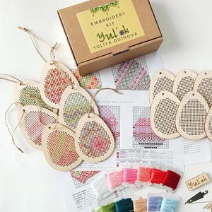 Puede incluir: Un conjunto de 10 kits de bordado de madera en forma de huevo con hilo de colores y una aguja. El kit incluye patrones para bordado de punto de cruz. La caja está etiquetada "Embroidery Kit Yuli'ok Yuliya Duinova".