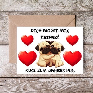 Könnte beinhalten: Eine weiße Grußkarte mit zwei beigen Mops-Hunden, die sich in der Mitte umarmen, umgeben von vier roten Herzen. Der Text DICH MOPST MIR KEINER! steht über den Hunden und der Text KUSS ZUM JAHRESTAG. steht unter den Hunden.