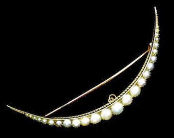 Op de afbeelding: Een halvemaanvormige broche met een goudkleurig frame en een rij witte parels. De parels variëren in grootte, de grootste in het midden. De broche heeft een speld aan de achterkant om vast te zetten.