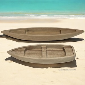 May include: Two wooden serving trays shaped like boats. The larger tray has a single compartment, while the smaller tray has two compartments. Both trays are made of light brown wood and have a natural finish.