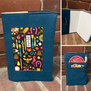 May include: A teal blue notebook cover with a colorful patterned window. The cover has a zippered pocket on the back with a key chain.