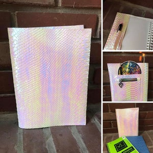 May include: A white iridescent binder with a snakeskin pattern. The binder has a zippered pocket on the front and a pen loop on the side.