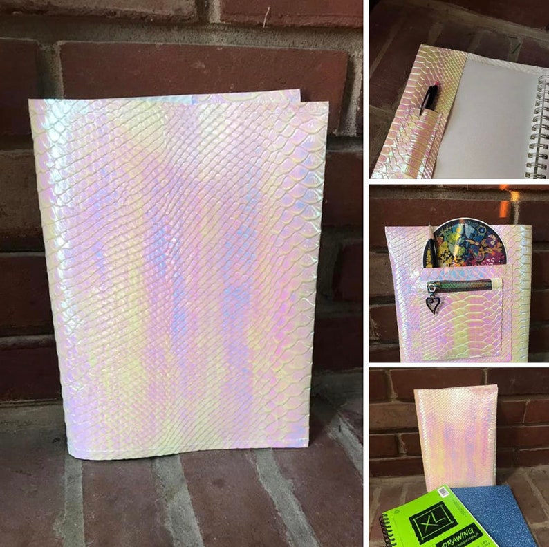 May include: A white iridescent binder with a snakeskin pattern. The binder has a zippered pocket on the front and a pen loop on the side.