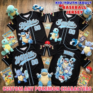 Op de afbeelding: Zwarte honkbalshirts met blauwe accenten en verschillende Pokemon-personages. De shirts tonen de namen "Blastoise", "Squirtle" en "Wartortle", evenals het nummer "00". Pluche speelgoed en ruilkaarten zijn ook zichtbaar.