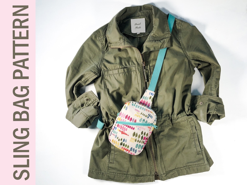 May include: A sling bag with a cream base and a colorful pattern of small, vertical, rounded shapes in shades of pink, yellow, green, and blue. The bag features a teal zipper and a matching teal strap. The bag is displayed over an olive green jacket.
