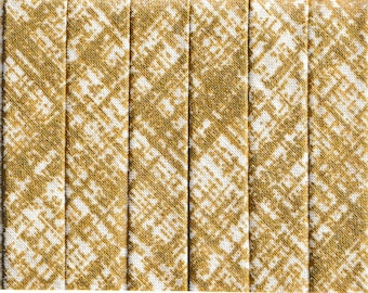 May include: Handmade double fold bias tape in a gold and white metallic pattern. The label reads "REFINERY METALLIC" and "100% Cotton". The tape is made by Studio e. The bias tape is a sewing and crafting supply.