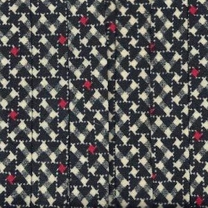 May include: A close-up of a black and white fabric with a red and white checkered pattern. The fabric has a subtle texture and a slightly faded look.