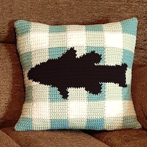 May include: A crocheted pillow with a blue and white gingham pattern and a black silhouette of a fish in the center.