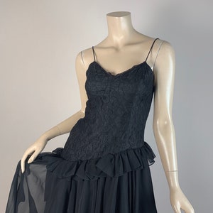 May include: A black lace and chiffon dress with a ruffled hem. The dress has a fitted bodice and a flowing skirt.