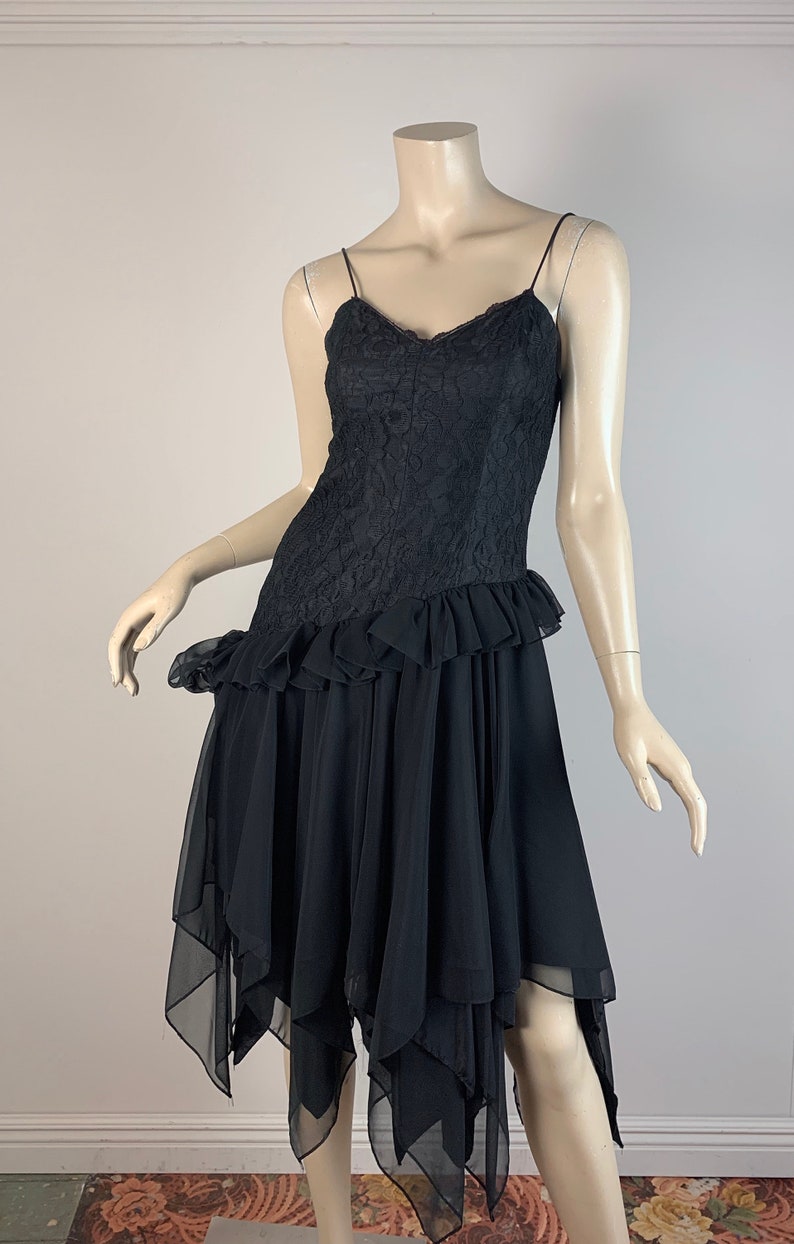 May include: A black lace and chiffon dress with a ruffled hem and a layered, asymmetrical skirt.