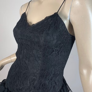 May include: A black lace dress with a ruffled hem. The dress has a V-neckline and spaghetti straps.