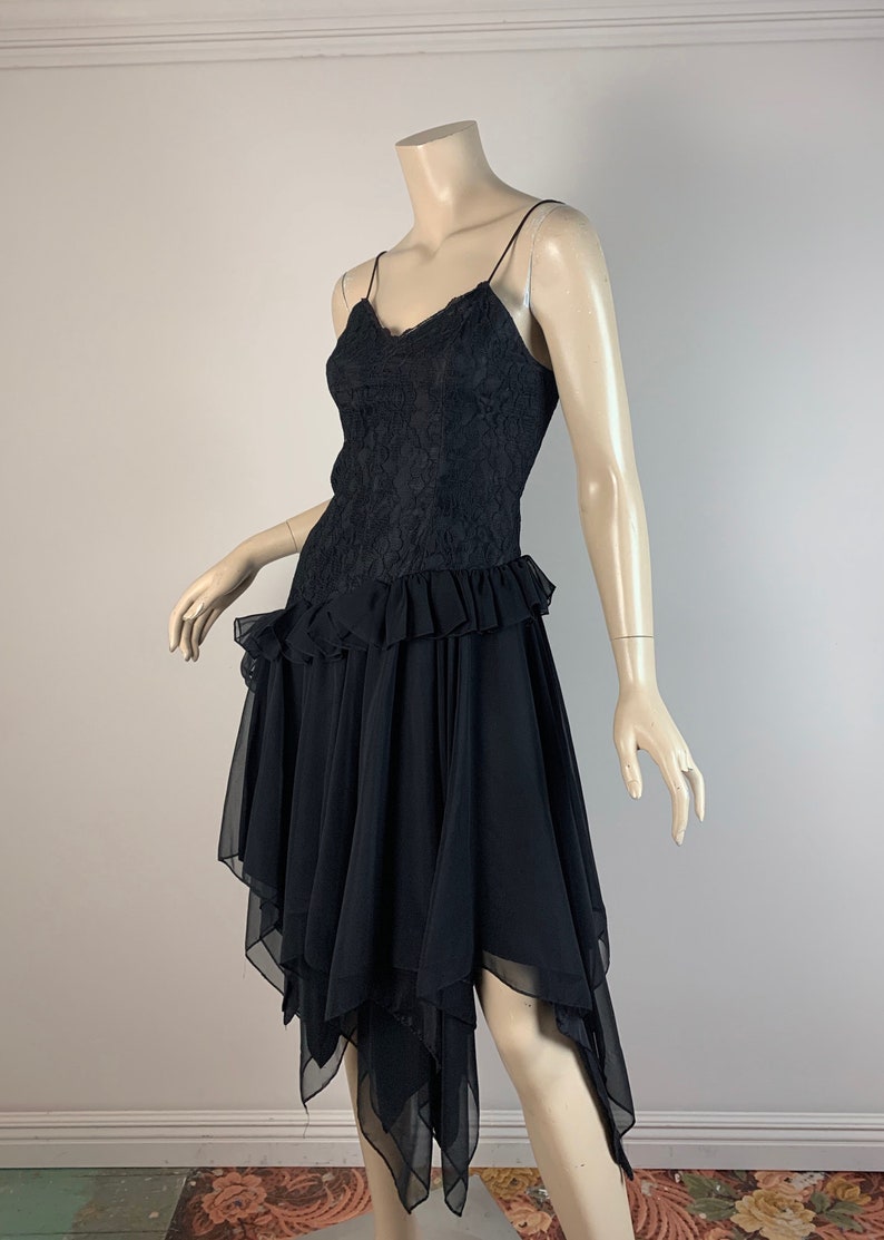 May include: A black lace and chiffon dress with a ruffled hem and a layered, asymmetrical skirt.