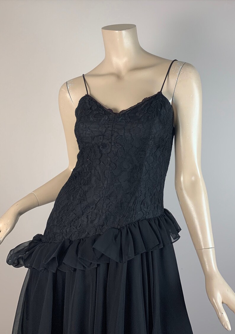 May include: A black lace dress with a ruffled skirt and spaghetti straps.