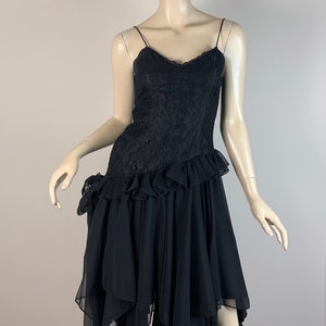 May include: A black lace and chiffon dress with a ruffled hem and an asymmetrical skirt. The dress has a sweetheart neckline and spaghetti straps.