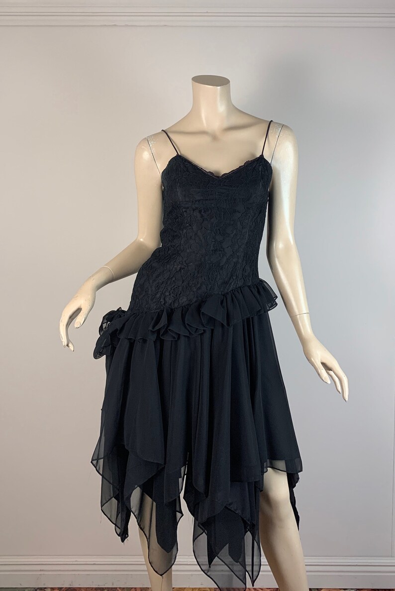 May include: A black lace and chiffon dress with a ruffled hem and an asymmetrical skirt. The dress has a sweetheart neckline and spaghetti straps.