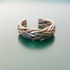 Op de afbeelding: Een zilveren gevlochten ring met een gladde, gepolijste afwerking.