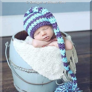 May include: A sleeping baby wearing a striped crochet hat with a long, dangling extension and a pom-pom. The hat features alternating stripes of purple and light blue. The baby is nestled in a light blue bucket lined with a white blanket. The text "Stocking Stripes Hat" is at the bottom.