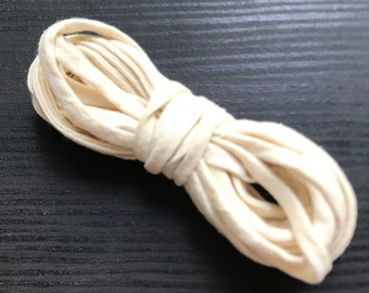 May include: A close-up of a white cotton cord, coiled and ready for use in a craft project.