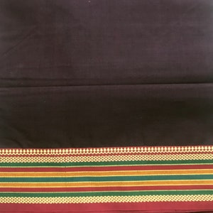 May include: A dark brown fabric with a decorative border. The border features a repeating pattern of white, red, and gold accents, with stripes of green, gold, and red. The fabric appears to be a textile, possibly for clothing or home decor.