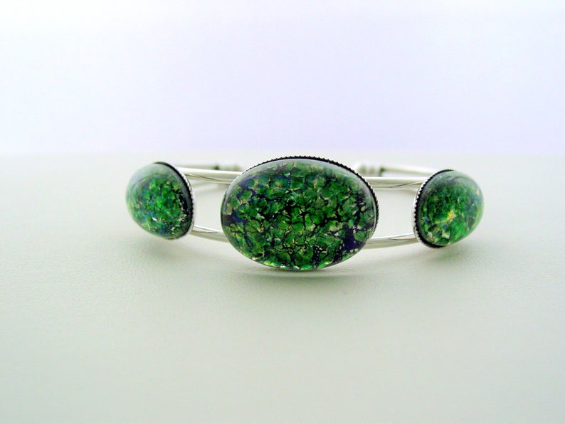 May include: Silver bangle bracelet with three green and blue oval-shaped glass cabochons.