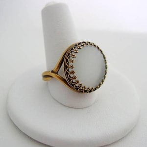 May include: A gold ring with a white oval stone set in a decorative filigree design.