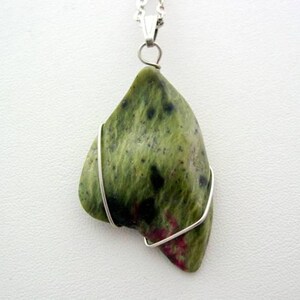 May include: A green and pink stone pendant with silver wire wrapping. The stone has a mottled pattern and is attached to a silver chain.