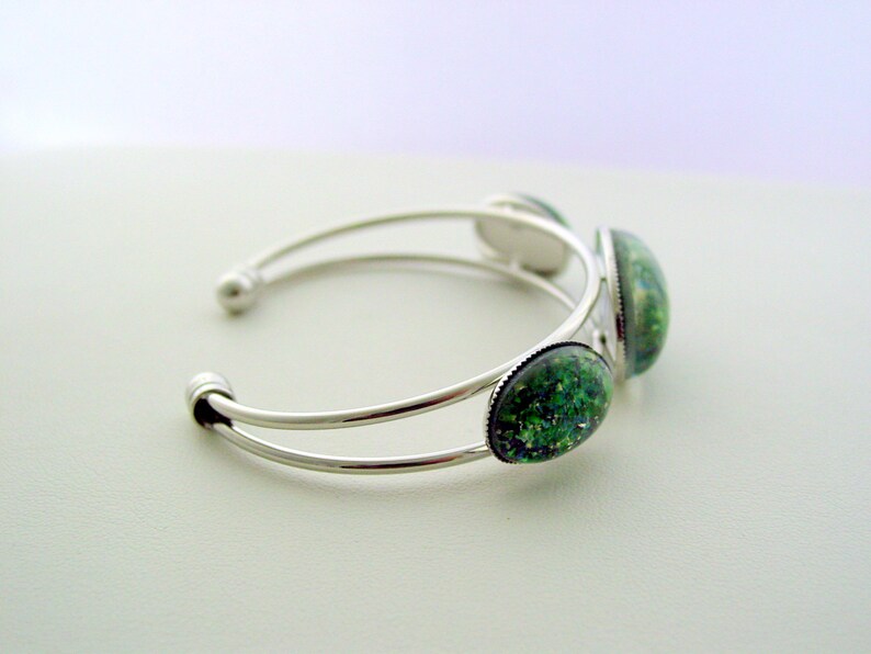 May include: Silver bangle bracelet with three green and blue oval-shaped cabochon stones.